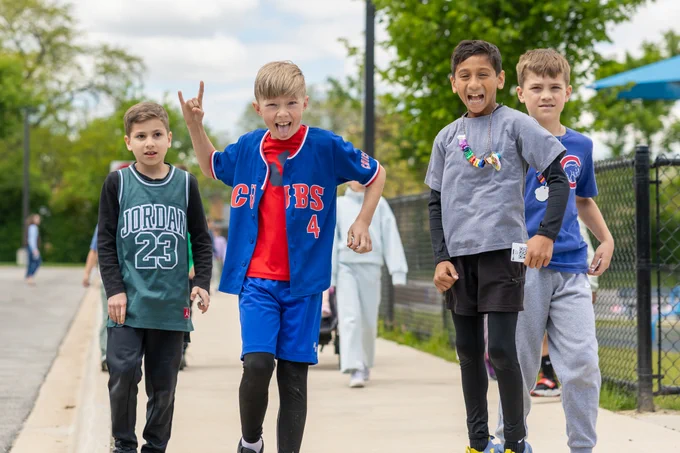 A group of children wearing sports jerseys enjoy a playful moment outdoors. Their expressions are lively and joyful, capturing the essence of youth and camaraderie.