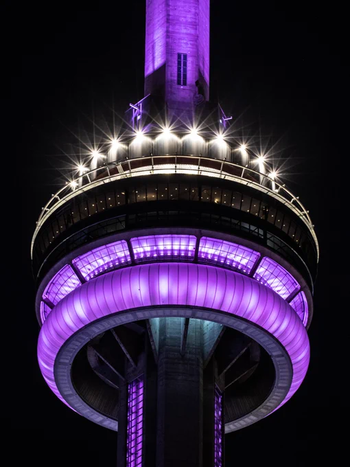 Closeup of the CN Tower at night lit purple / Gros plan de la Tour CN illuminée en violet la nuit 