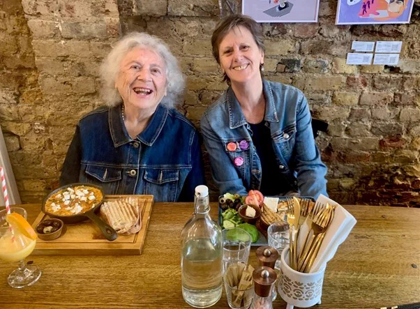 Two women in a pub with plates of food in front of them
