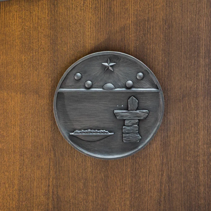 The coat of arms for the territory of Nunavut, featuring the midnight sun, the North Star, a qulliq, and an inuksuk.