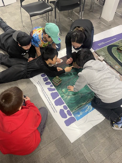 Students sitting on the floor looking at a map.