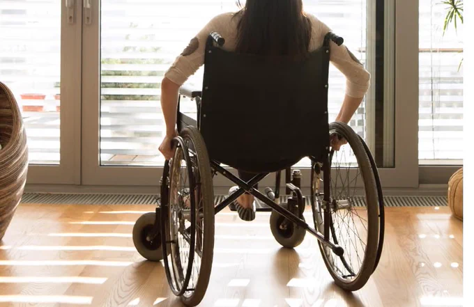 a woman in a wheelchair with her back to the camera looking out a window