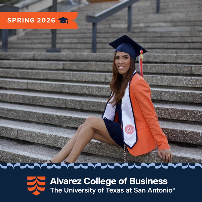 Vanessa Aquino in cap, gown, and orange blazer sitting on campus steps at University of Texas at San Antonio, Spring 2026.