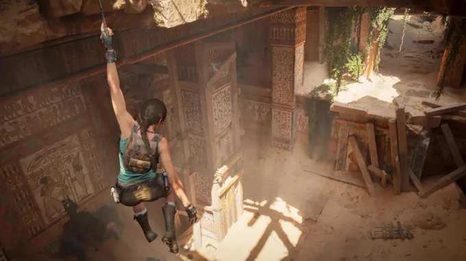 a screenshot from Tomb Raider: Legacy of Atlantis that shows Lara Croft hanging above Egyptian ruins while sunlight bathes the sand below