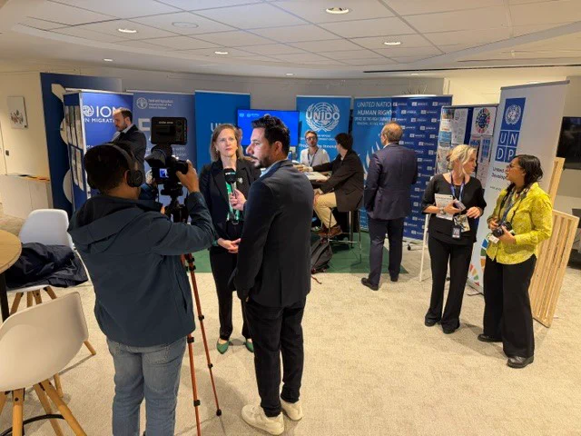 Veronika Hunt Safrankova, in the front, being interviewed, with in the back the UN stand.