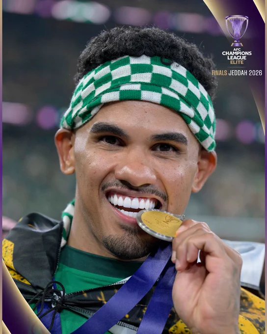 A joyous athlete bites a gold medal during the AFC Champions League Finals in Jeddah. The excitement of victory is evident.