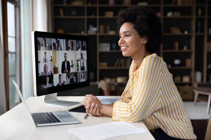 A person sits at a desk participating in a video conference on a computer. 