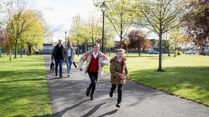 image of young people running with parents walking behind