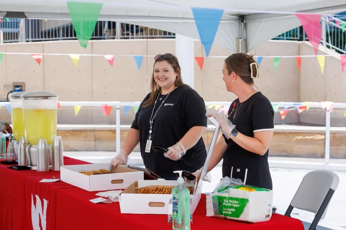 University employees standing behind a tables serving cookies. 