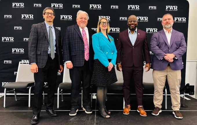 A group of five people standing in front of a black backdrop with "FWR" repeatedly printed on it. They are dressed in business attire and smiling for the camera.