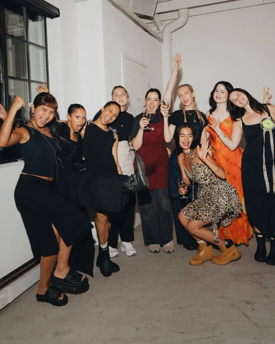 An image of multiple people smiling in a white room.