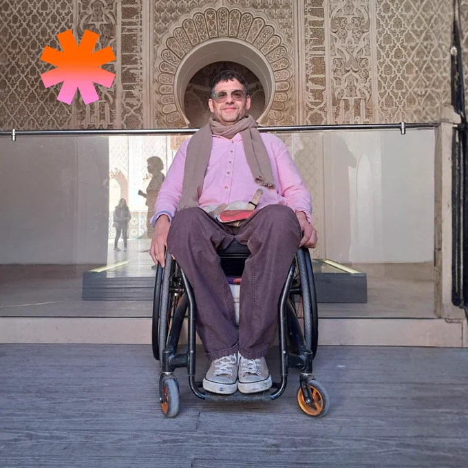 Photo of Justin smiling at the camera in front of an ornate, mosaic-style wall.