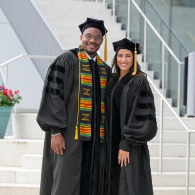 Two students; student on the left wearing stoles from the Deborah Harmon-Hines, PhD, Commencement Celebration at graduation