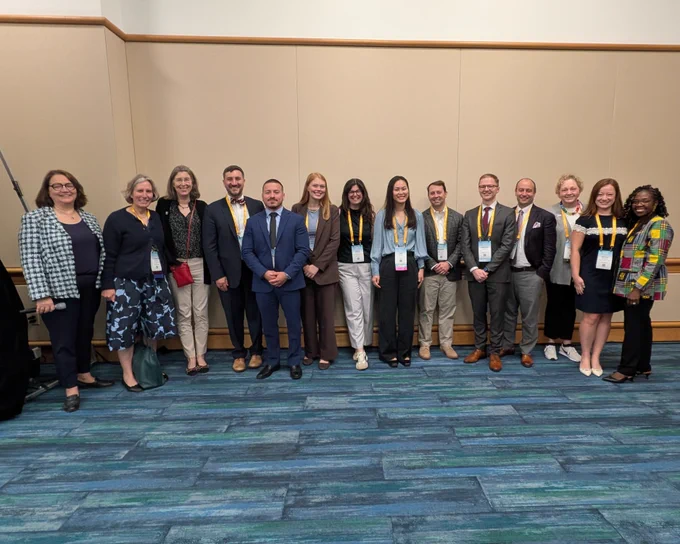 A group of 14 people from the Discover program stand together for a picture indoors