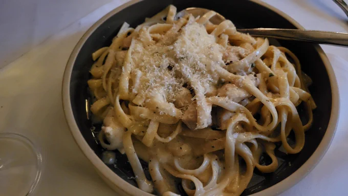 A bowl of fettuccine alfredo with fresh grated parmesan cheese