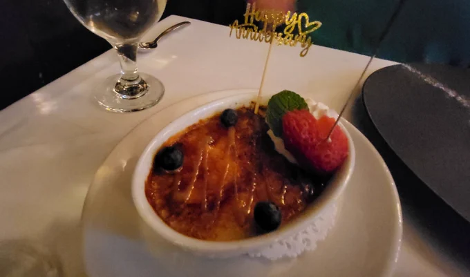 Creme Brulet, garnished with a sliced strawberry and a mint leaf, and the words Happy Anniversay.