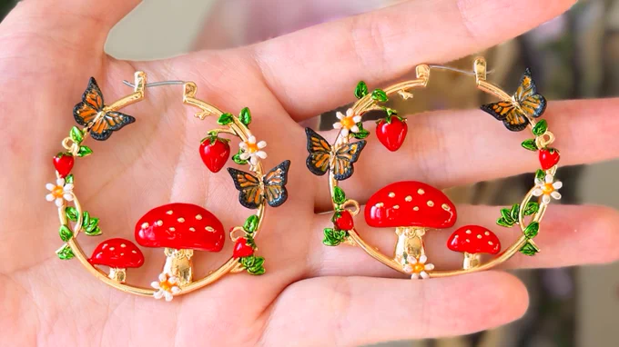 golden earring hoops with mushrooms, butterflies, strawberries and daisies coming off of it