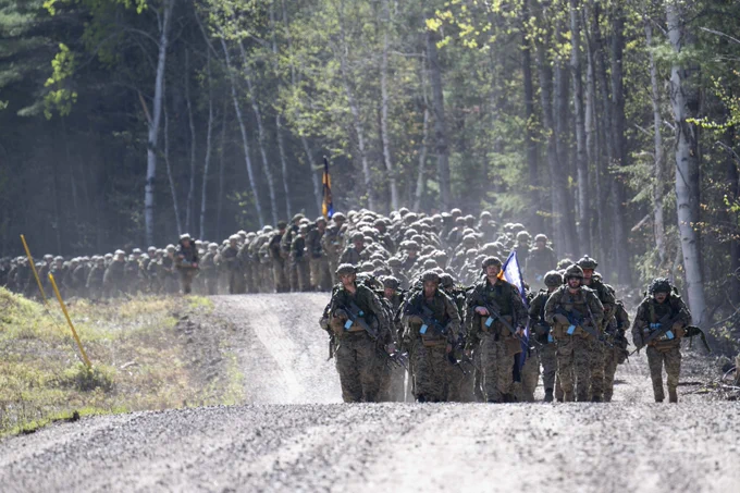 A large group of soldiers in full gear marching along a trail.