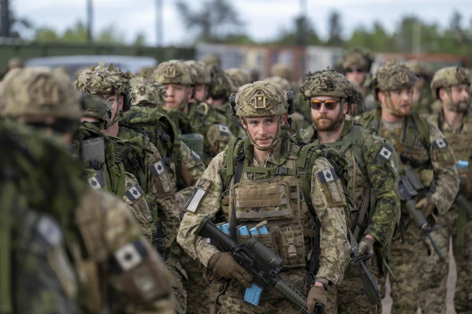 A line of soldiers carrying rifles and backpacks.