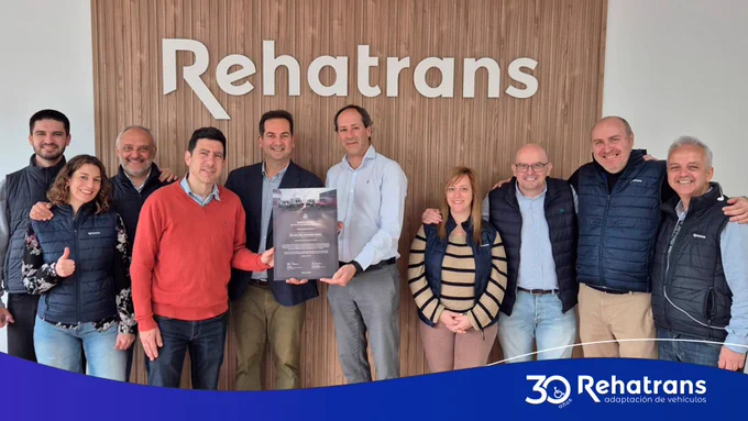 Equipo de Rehatrans posando sonriente frente al logo de la empresa; dos personas sostienen un certificado.