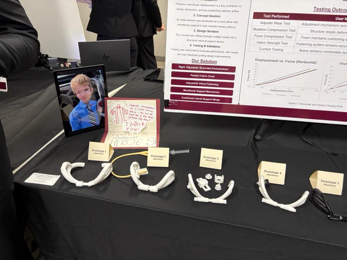 A display table featuring a tablet with a photo of a smiling child, several prototypes labeled 1 through 5, a thank-you card, and a poster with testing outcomes and solutions for orthopedic devices.