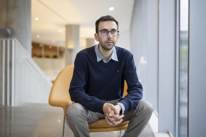 U of T Engineering professor Nicolas Papernot sitting on a chair and looking out a window.