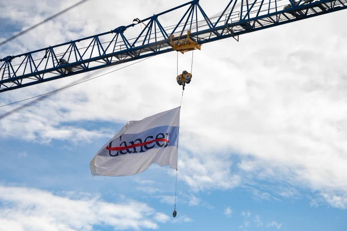 Photo of a flag hanging from a crane.