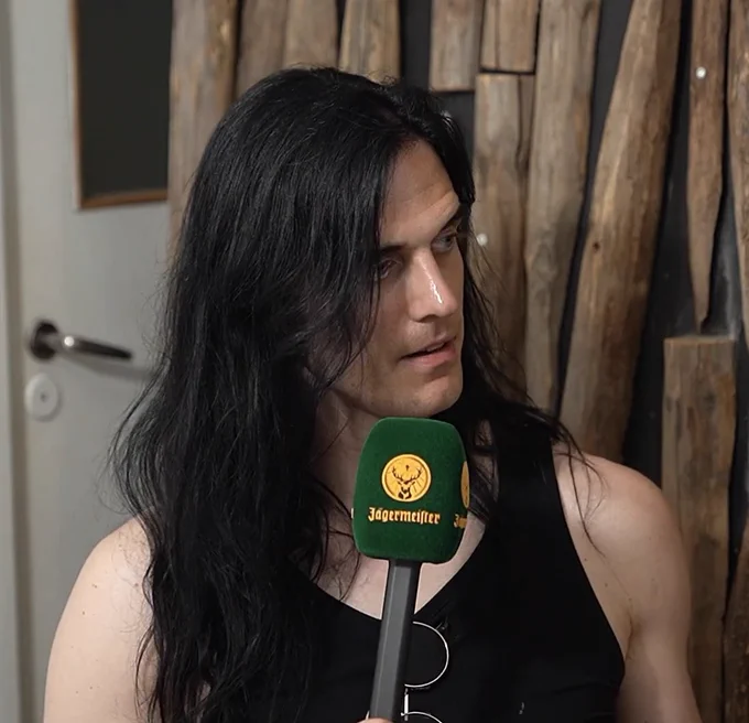 johannes eckerström during an interview holding a microphone and looking to the side 