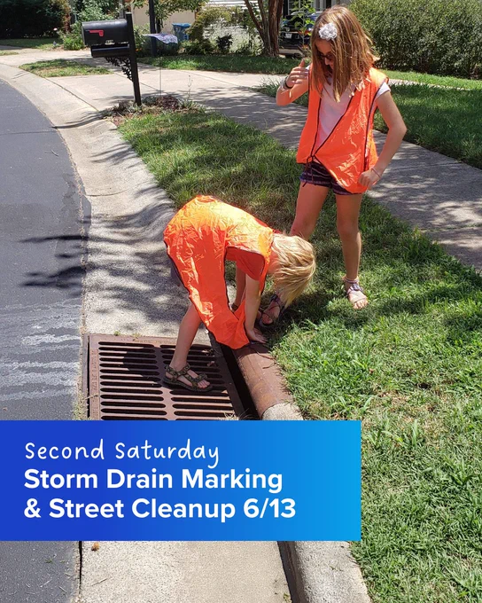 Two people wearing orange vests work near a street drain on a sunny day. The image has a caption that reads "Second Saturday Storm Drain Marking & Street Cleanup 6/13.