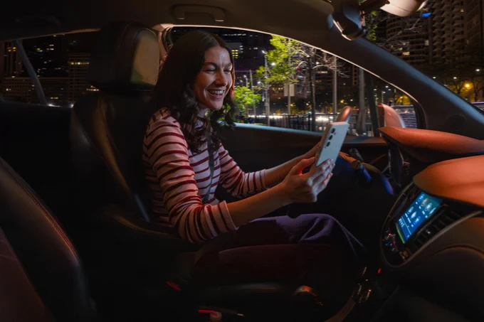 Photo from the passenger seat
of a young woman looking at her phone while driving at night. 