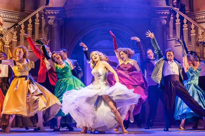 A photo showing a group of performers in lavish attire dancing on stage 