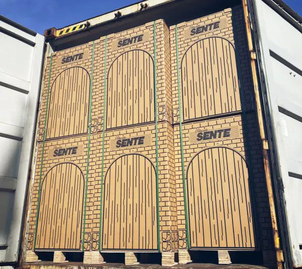 Shipping container doors painted to resemble six wooden arched doors with brick wall detailing and the word 'SENTE' above each arch.