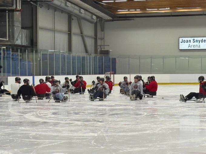 Un groupe de personnes rassemblées sur une patinoire lors d’une partie de hockey sur luge.
