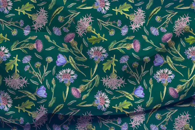 Print fabric swatch featuring a purple thistle flower, bluebells, and cornflowers, fancifully scattered on an emerald green backdrop, creates a charming Cottagecore pattern inspired by European meadow flora and vintage botanical illustrations. Colorful floral design with a Scottish twist. This pattern is also available as wallpaper, bedding, and more home decor print-on-demand items. Check out my Canis Art Studio shop on Spoonflower and grab your favorite designs at a discounted price. 