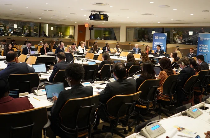 Wide view of the UN Youth Office briefing at UN Headquarters, showing a full conference room of Member State representatives and participants seated around tables.
