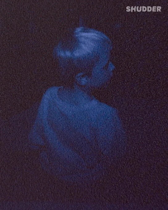 A grainy blue-tinted image of a child viewed from behind. The mood is mysterious and somewhat unsettling, evoking a sense of intrigue or suspense.
