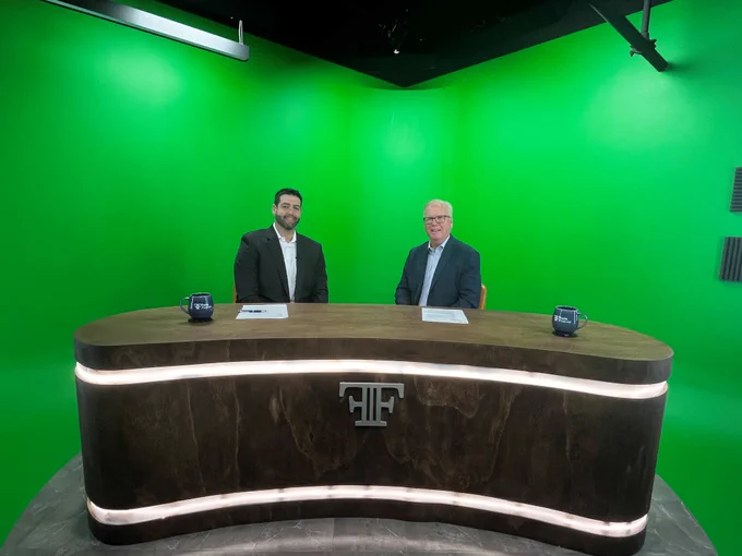 DRS Commissioner Mark Boughton sits with Ben Fuchs of Fuchs Financial in front of a green screen during a taping. 