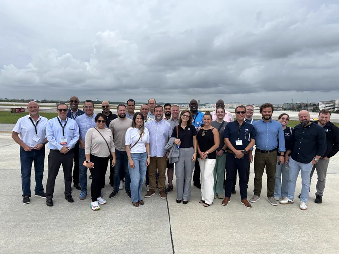 Attendees of the 2026 Airports Conference of the Americas take a photo on the airfield at FLL.