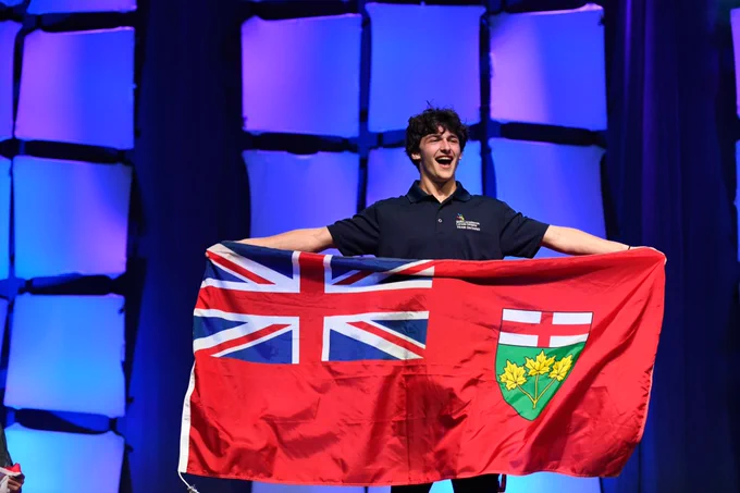 Student holds up the Ontario flag on stage.