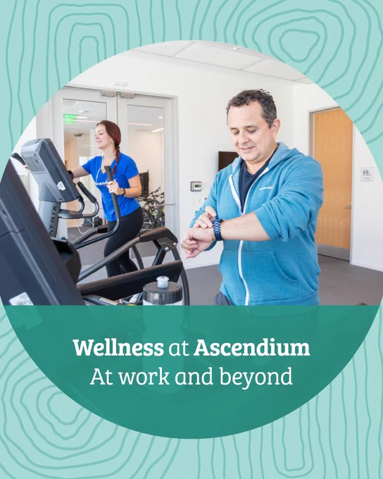 Two people are in a gym setting at Ascendium, using exercise equipment. One is on a treadmill and another is adjusting a smartwatch. The text reads, "Wellness at Ascendium: At work and beyond."