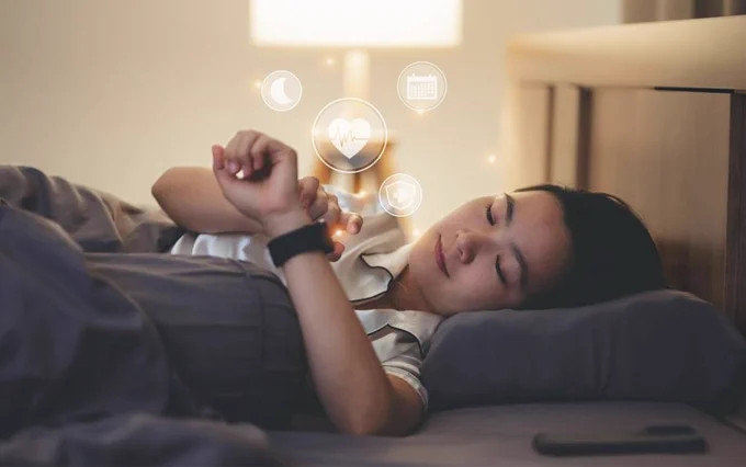 A woman using a smart watch while lying in bed. Researchers are using smart wearable devices to measure sleep, heart rate, and activity patterns. Credit: iStock