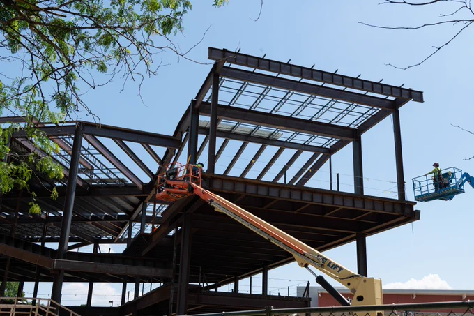 Construction crews install steel beams on the future three-story Library Commons building.