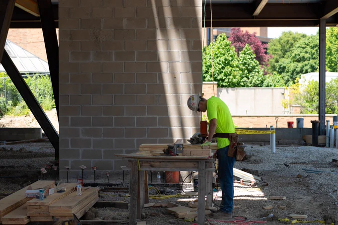 Construction worker measures lumber inside the future Library Commons building on the UIS campus.