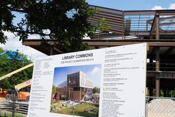 Sign displays rendering of the future Library Commons as construction continues behind it.