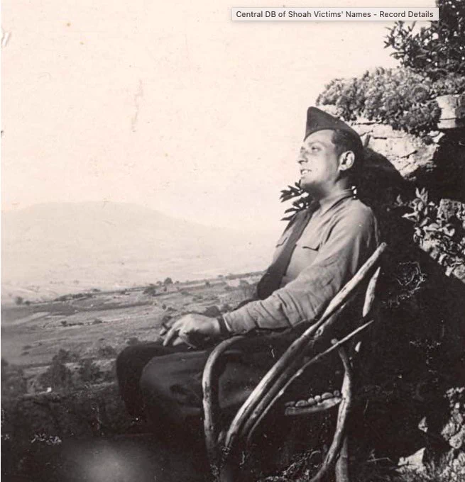 Photograph showing an individual in military uniform sitting on a wicker chair outdoors, overlooking a scenic landscape.