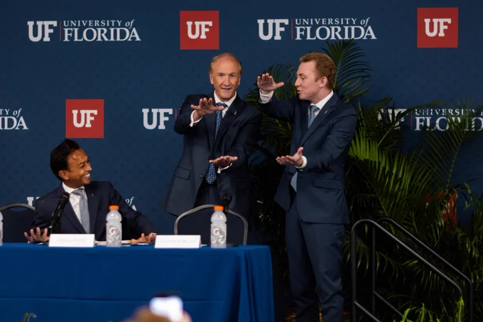 Dr. Stuart Bell doing The Gator Chomp on stage with the student body president.