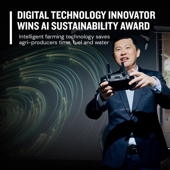 Image of a middle aged man standing in front of a simulation screen, holding a device that controls a mobile piece of technology. 