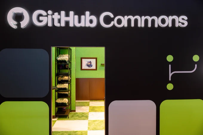 Entrada al espacio GitHub Commons en el #MSBuild 2026, con decoración temática en verde y una estantería con merchandising visible al fondo.