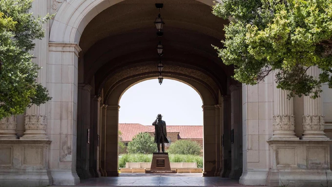 View of the archway of the Administration Building and Preston Smith Statue on the campus of Texas Tech University.