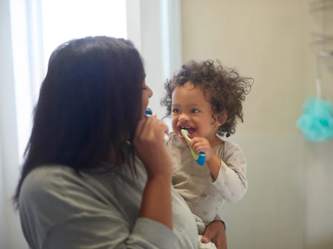 baby and mother brushing teeth in bathroom, learning and cleaning in their home. 
